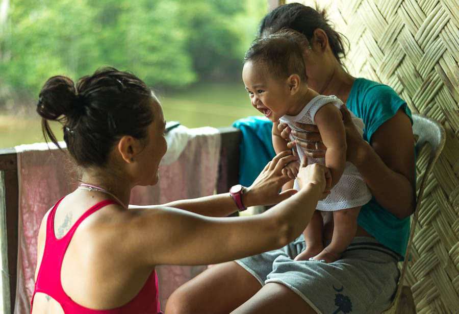 Irene juega con bebe en una casa Filipina donde nos acogieron, Port Barton, Filipinas