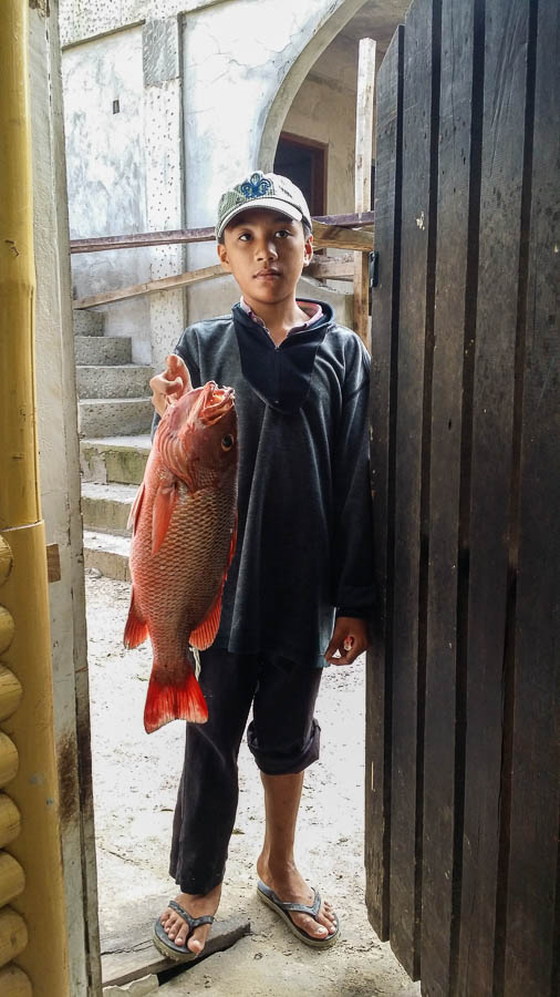 Niño muestra un pez recién pescado. Port Barton, Filipinas