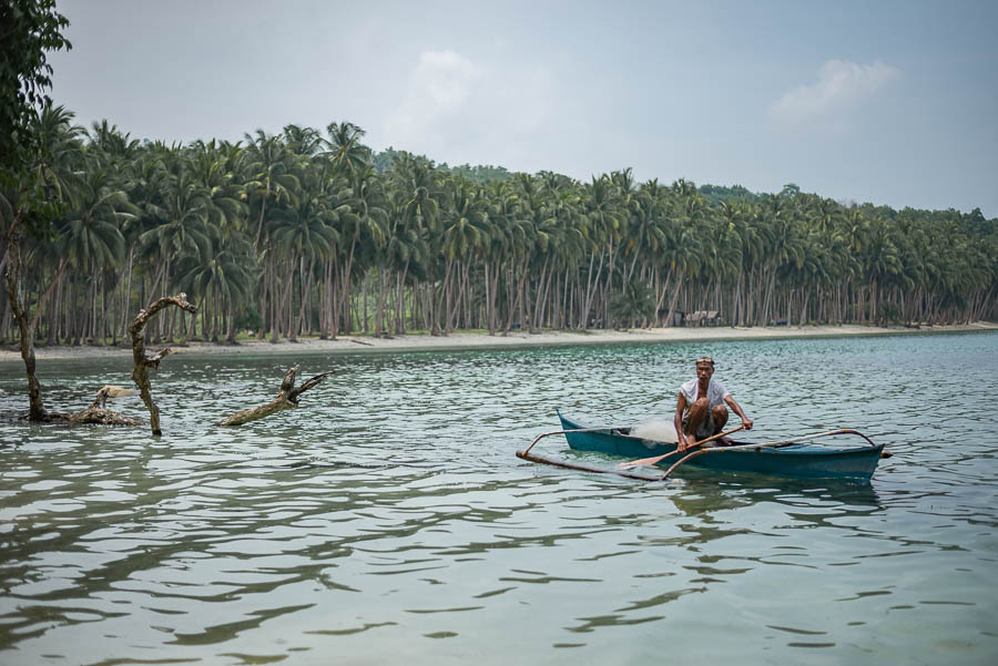 Hombre pescando en barca, White beach, Port Barton, Filipinas